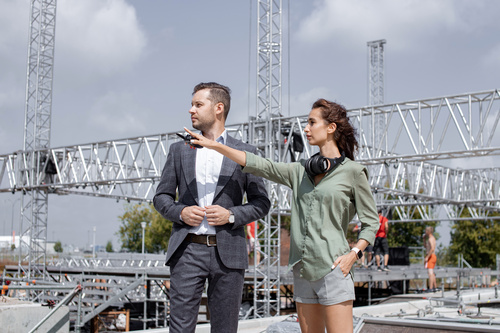 Mann und Frau beim Koordinieren einer Veranstaltung vor einer Bühne im Aufbau