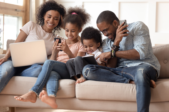 Familie konsumiert lachend digitales Produkte