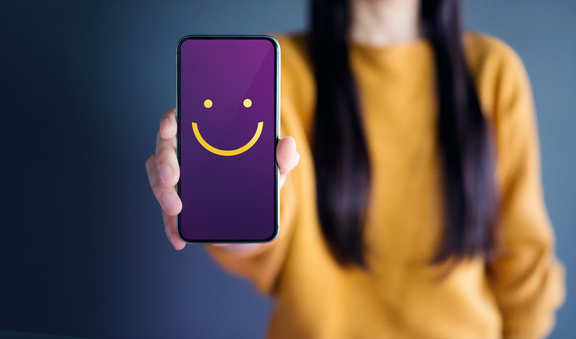Woman shows mobile phone with smiley on the display