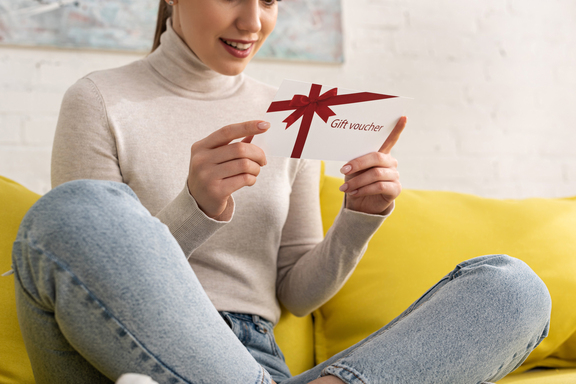 Young woman holding gift certificate in her hands